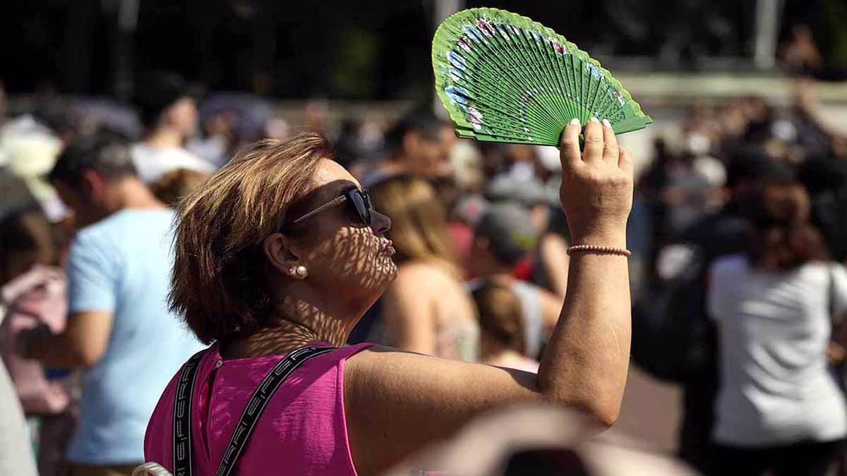 A woman seeks shade in the sun while passing in front of Buckingham Palace in London. (File Photo: AP)